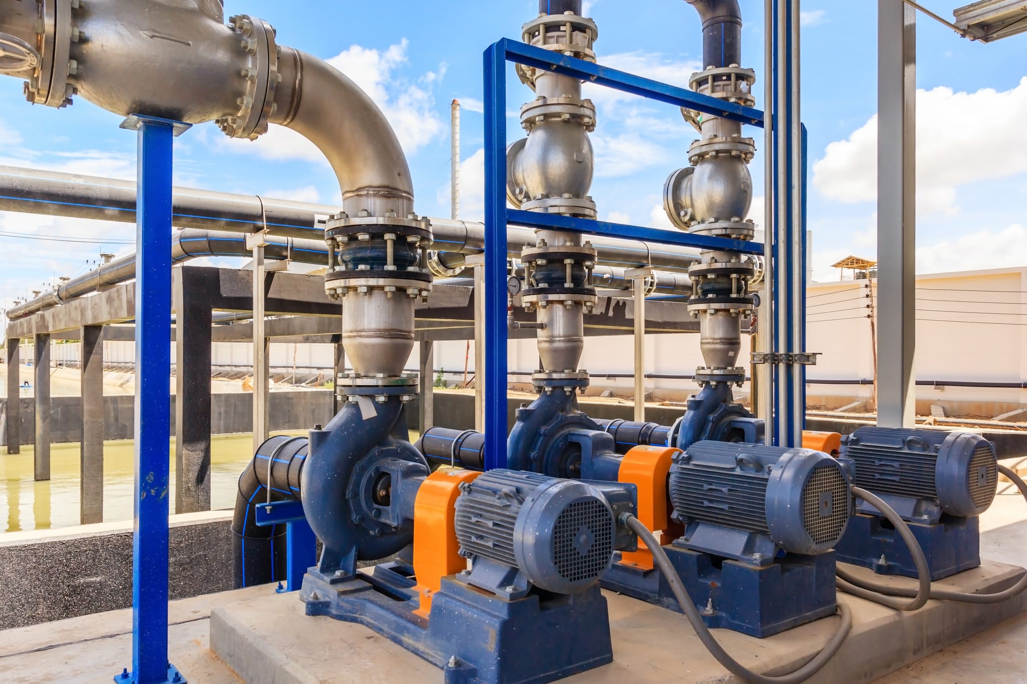 Outdoor industrial pump train with motors, discharge piping and process water pond