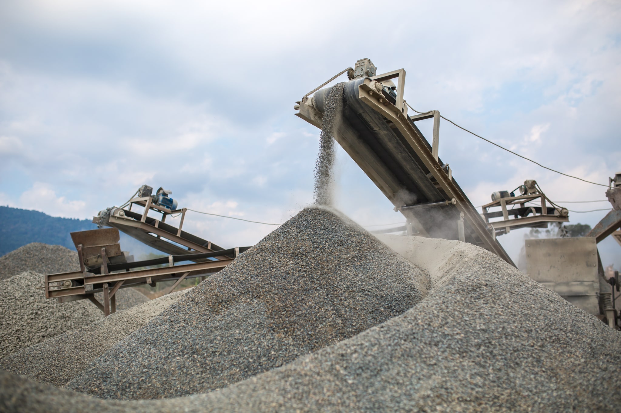 Trailer-mounted trommel wash plant: oversize rocks discharge at the open drum end; undersize slurry falls through perforations onto a side riffled sluice